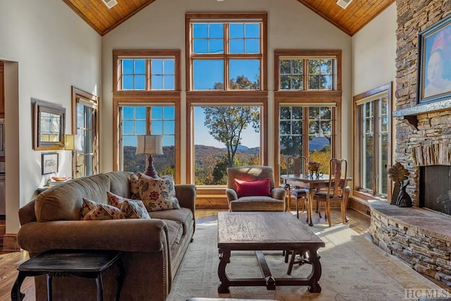 living room featuring wood ceiling, a stone fireplace, a mountain view, and high vaulted ceiling