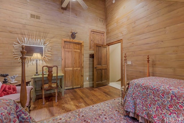 bedroom with hardwood / wood-style flooring, ceiling fan, and wood walls