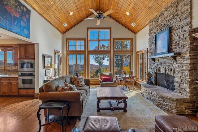 living room with a stone fireplace, high vaulted ceiling, dark hardwood / wood-style floors, and ceiling fan