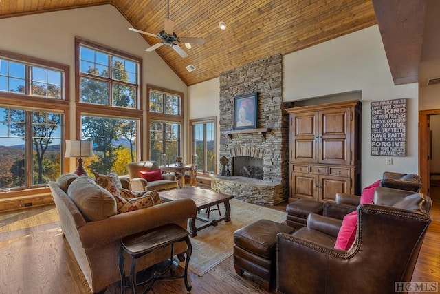 living room with hardwood / wood-style flooring, wood ceiling, a stone fireplace, and high vaulted ceiling