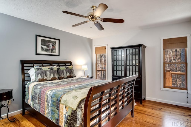 bedroom with ceiling fan, light wood-type flooring, and a textured ceiling