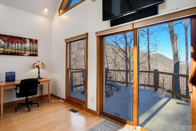 entryway with a mountain view, high vaulted ceiling, built in desk, and light hardwood / wood-style flooring