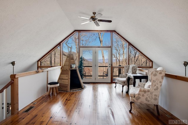 unfurnished room featuring ceiling fan, vaulted ceiling, a textured ceiling, and hardwood / wood-style floors