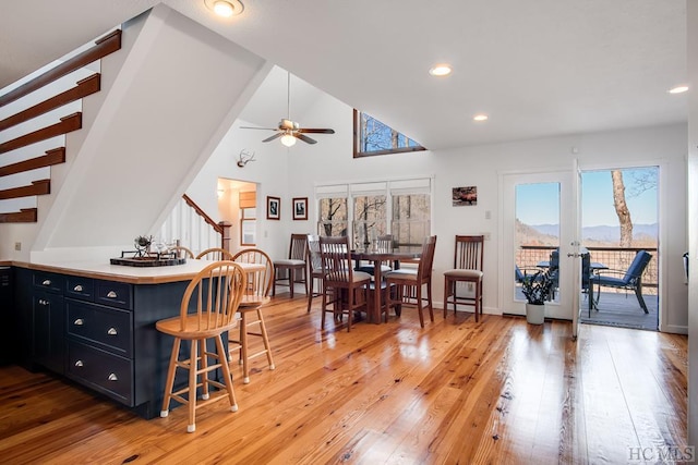 interior space featuring ceiling fan, hardwood / wood-style flooring, a kitchen bar, and a wealth of natural light