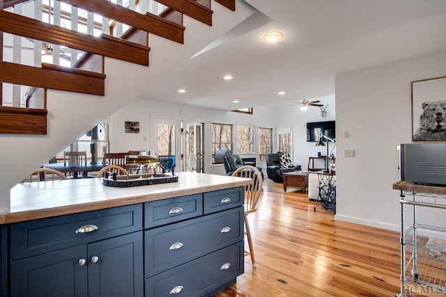 kitchen featuring blue cabinetry, lofted ceiling, ceiling fan, and light hardwood / wood-style flooring