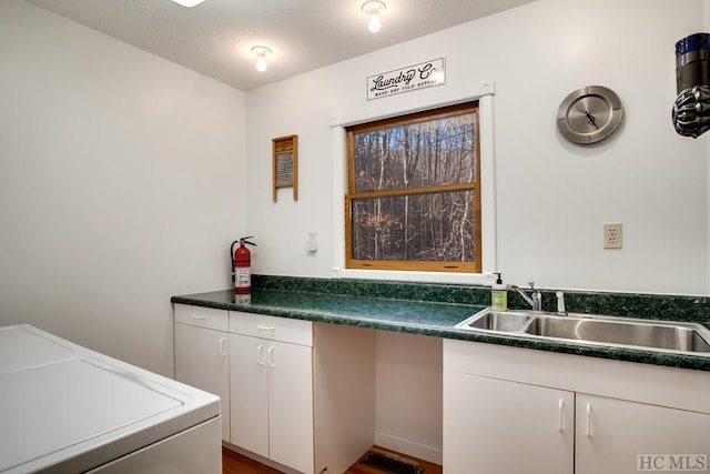 laundry room with cabinets, washing machine and dryer, sink, and a textured ceiling