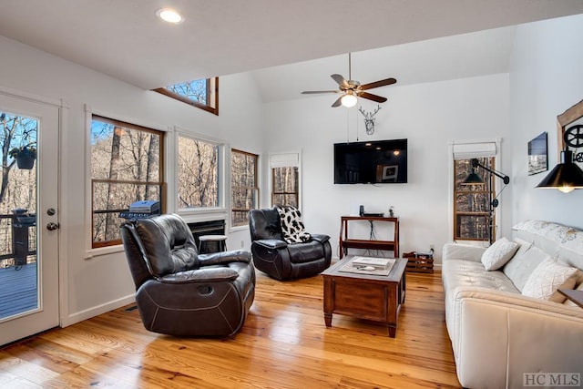 living room featuring ceiling fan, light hardwood / wood-style floors, and vaulted ceiling