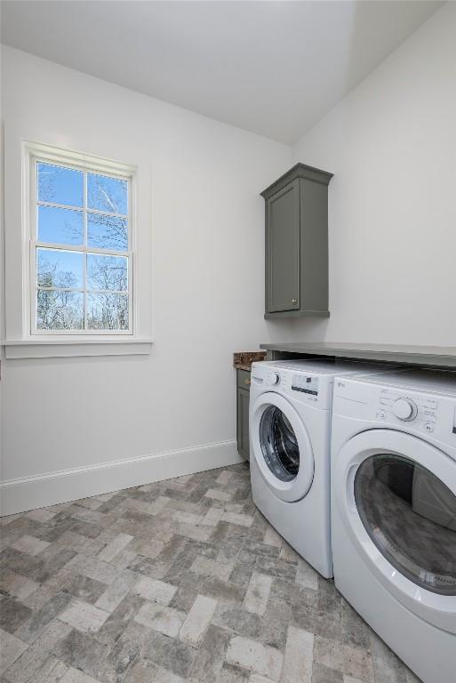 laundry area with baseboards, washing machine and clothes dryer, and cabinet space