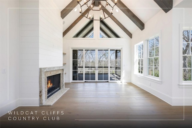 unfurnished living room featuring plenty of natural light, a fireplace, beamed ceiling, and wood finished floors