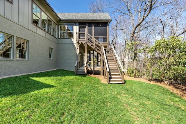 back of house featuring stairs, a yard, board and batten siding, and a sunroom