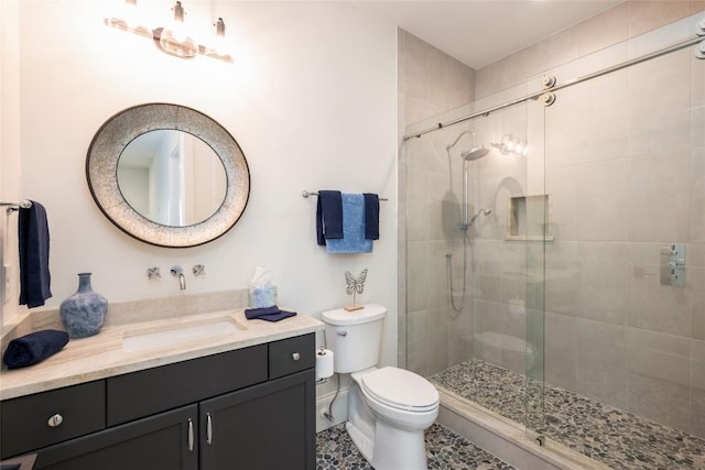 bathroom with toilet, vanity, baseboards, and a shower stall