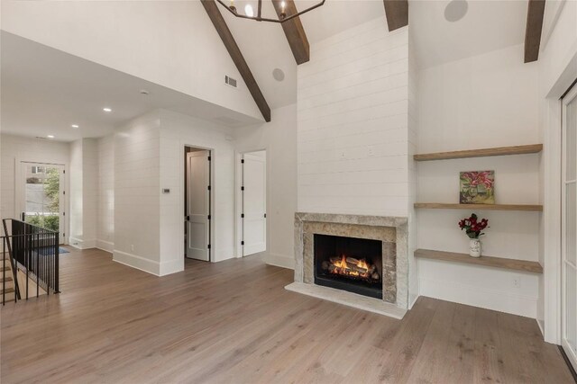 2608 Magnolia Dr, Highlands, NC 28741 - unfurnished living room featuring beamed ceiling, wood finished floors, a warm lit fireplace, high vaulted ceiling, and a chandelier