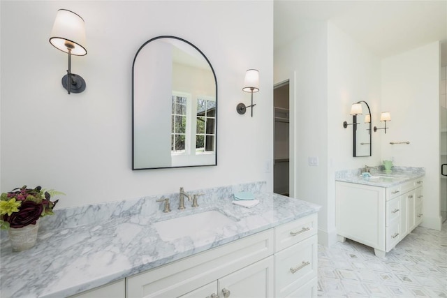 bathroom with two vanities, a sink, and a spacious closet