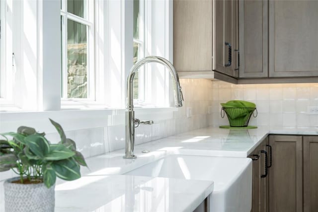details with a sink, tasteful backsplash, and light stone countertops