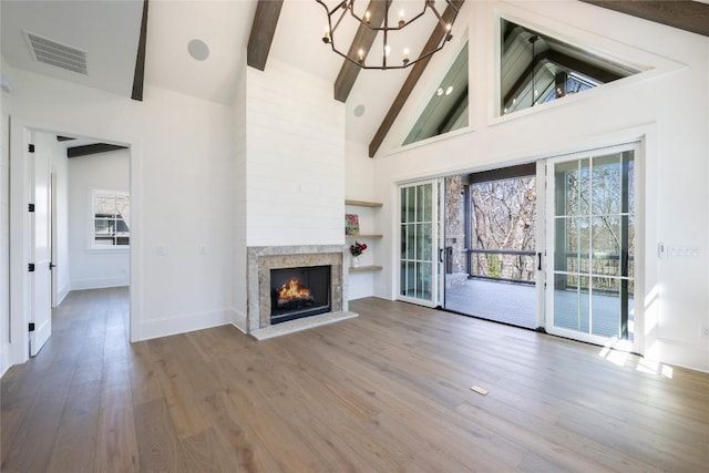 unfurnished living room featuring a chandelier, visible vents, beam ceiling, high vaulted ceiling, and a high end fireplace