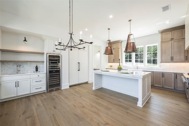 unfurnished living room with baseboards, an inviting chandelier, lofted ceiling with beams, a warm lit fireplace, and wood finished floors