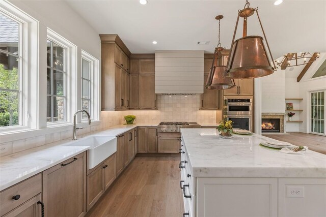 2608 Magnolia Dr, Highlands, NC 28741 - kitchen with light wood-type flooring, a center island, custom exhaust hood, light stone countertops, and recessed lighting