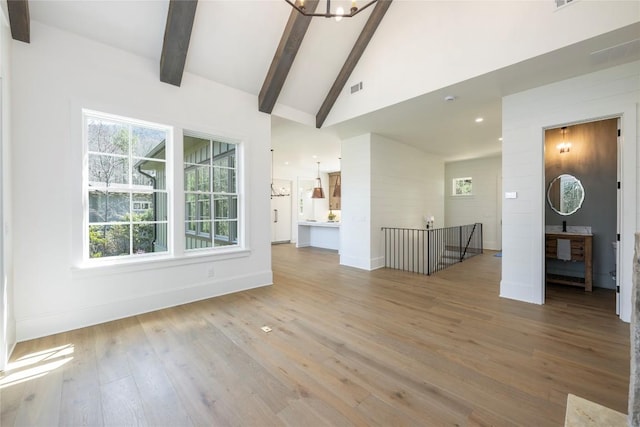 unfurnished living room featuring high vaulted ceiling, visible vents, wood finished floors, baseboards, and beam ceiling