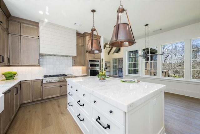 kitchen featuring stainless steel appliances, light wood finished floors, a healthy amount of sunlight, and decorative backsplash