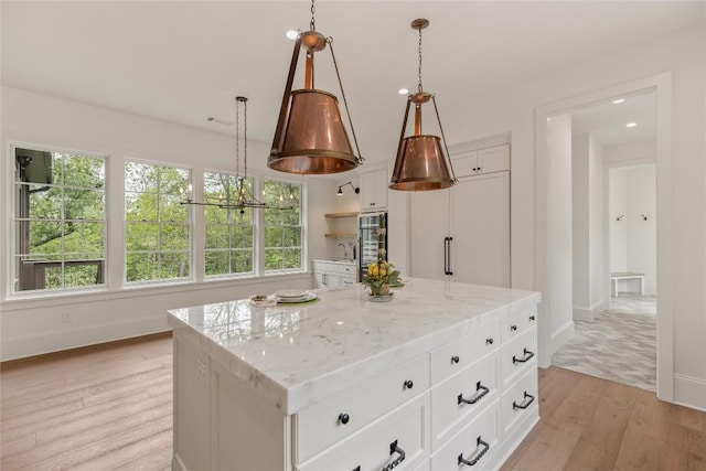 2608 Magnolia Dr, Highlands, NC 28741 - kitchen with light wood-style flooring, white cabinetry, light stone counters, and pendant lighting