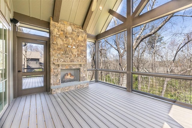 unfurnished sunroom with beam ceiling, an outdoor stone fireplace, and plenty of natural light
