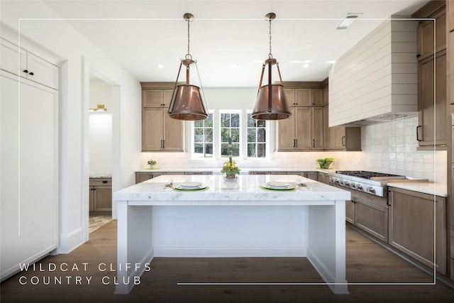 kitchen featuring stainless steel gas stovetop, a center island, light stone counters, decorative backsplash, and dark wood-style floors