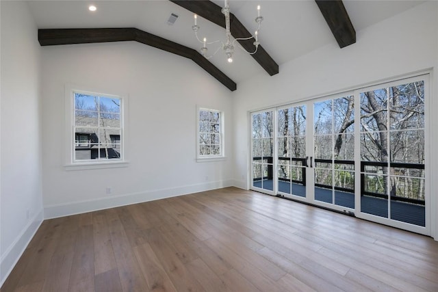 empty room with a chandelier, baseboards, beam ceiling, and wood finished floors