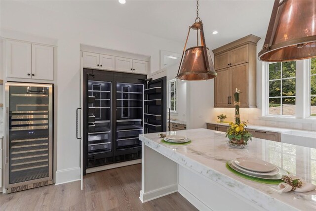 2608 Magnolia Dr, Highlands, NC 28741 - kitchen featuring beverage cooler, light stone countertops, wood finished floors, hanging light fixtures, and recessed lighting