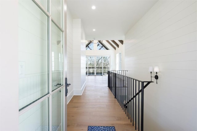 hall featuring recessed lighting, lofted ceiling, an upstairs landing, and wood finished floors