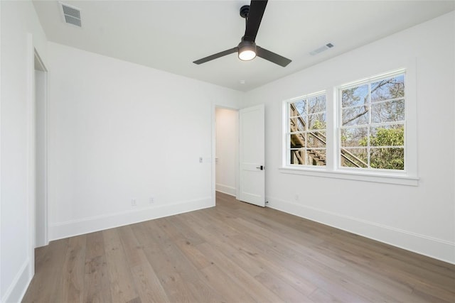 unfurnished room with wood finished floors, baseboards, and visible vents