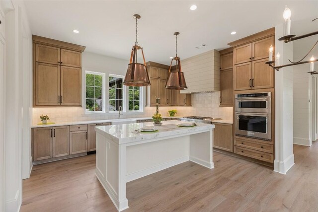 2608 Magnolia Dr, Highlands, NC 28741 - kitchen featuring appliances with stainless steel finishes, light wood-style flooring, tasteful backsplash, a kitchen island, and pendant lighting