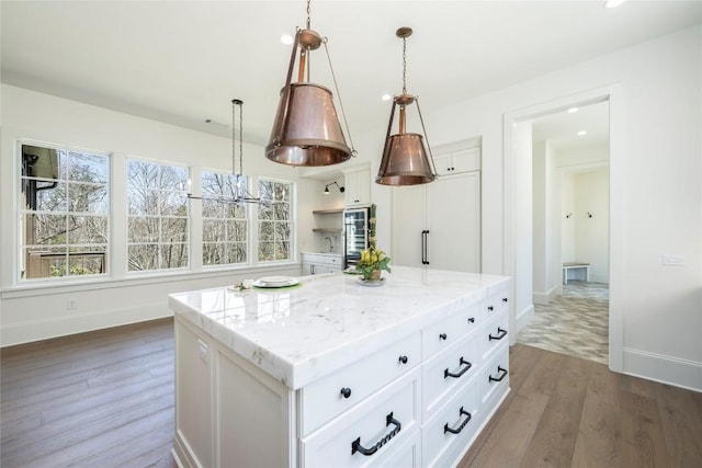 kitchen featuring a center island, white cabinetry, pendant lighting, and wood finished floors
