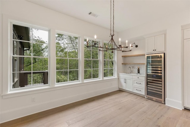 2608 Magnolia Dr, Highlands, NC 28741 - indoor bar with wine cooler, a chandelier, light wood finished floors, decorative backsplash, and pendant lighting