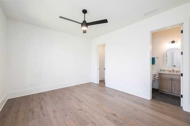 unfurnished bedroom with light wood-style floors, ensuite bath, visible vents, a sink, and baseboards