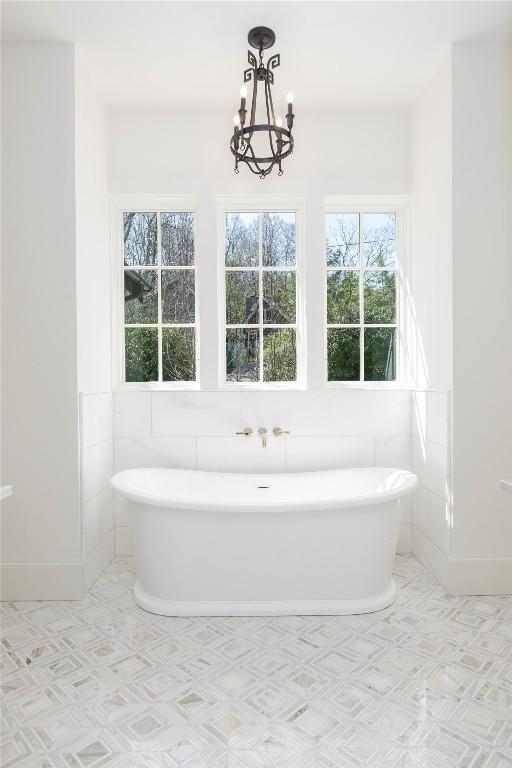 bathroom with a freestanding bath, baseboards, and an inviting chandelier
