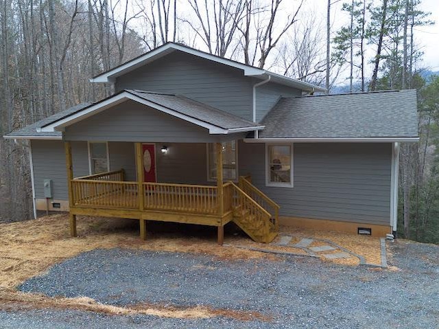 view of front of property with covered porch, a shingled roof, and crawl space