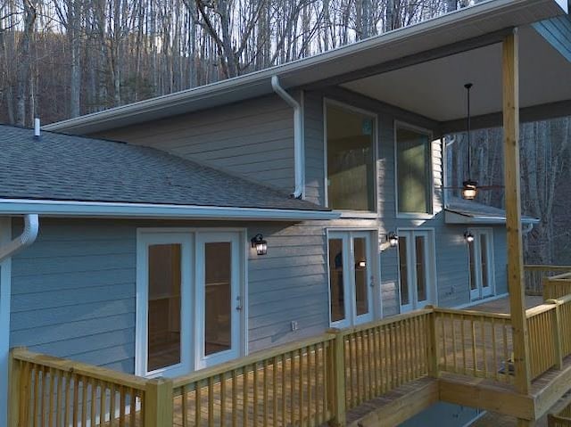 exterior space with a deck and roof with shingles