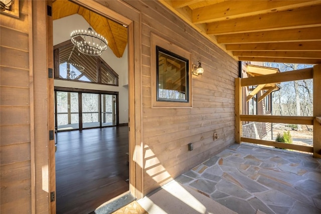 1086 Roaming Rd, Glenville, NC 28736 - hallway featuring an inviting chandelier, stone floors, wooden walls, and beamed ceiling