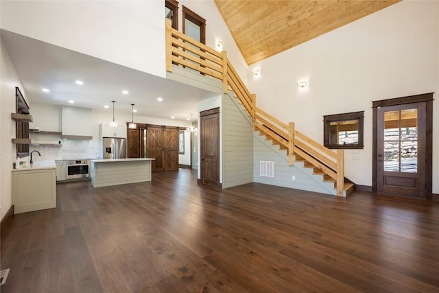 1086 Roaming Rd, Glenville, NC 28736 - unfurnished living room with dark wood-style flooring, high vaulted ceiling, stairway, a barn door, and a sink