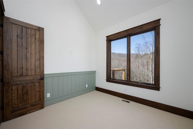 1086 Roaming Rd, Glenville, NC 28736 - spare room featuring carpet floors, visible vents, vaulted ceiling, and a wainscoted wall