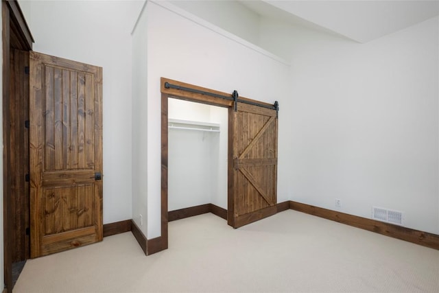 1086 Roaming Rd, Glenville, NC 28736 - unfurnished bedroom featuring baseboards, carpet floors, a barn door, visible vents, and a closet