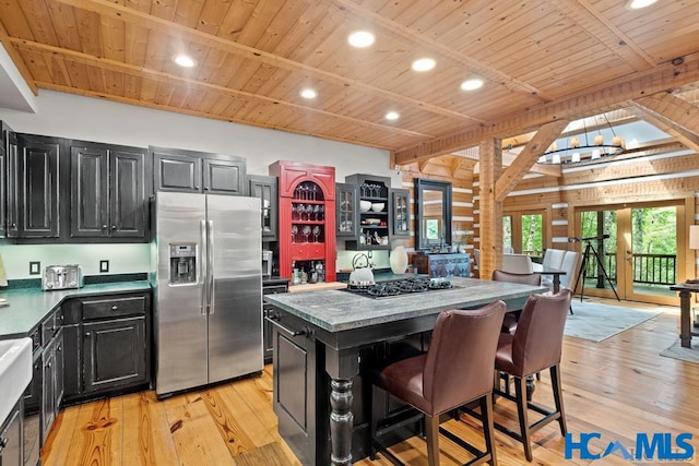 kitchen with light wood-style floors, wood ceiling, stainless steel fridge, and dark cabinetry