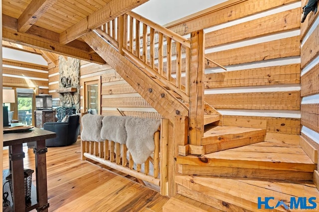 stairs featuring wood walls, hardwood / wood-style floors, and beamed ceiling