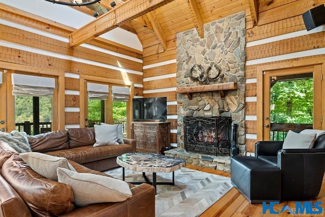 living area featuring high vaulted ceiling, a stone fireplace, wooden walls, wood finished floors, and beam ceiling