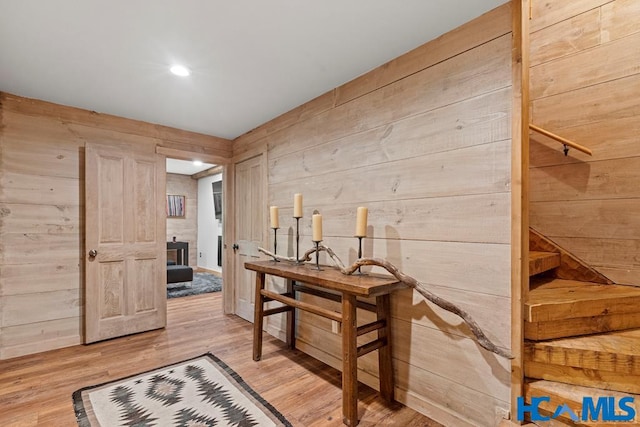 corridor with light wood finished floors and wood walls