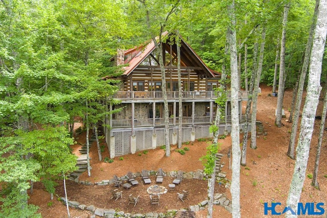 back of property with stone siding, log exterior, stairway, and a forest view