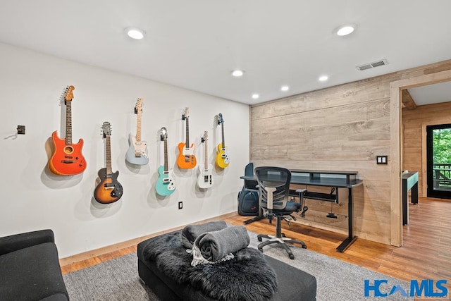 office space featuring wood walls, wood finished floors, visible vents, and recessed lighting