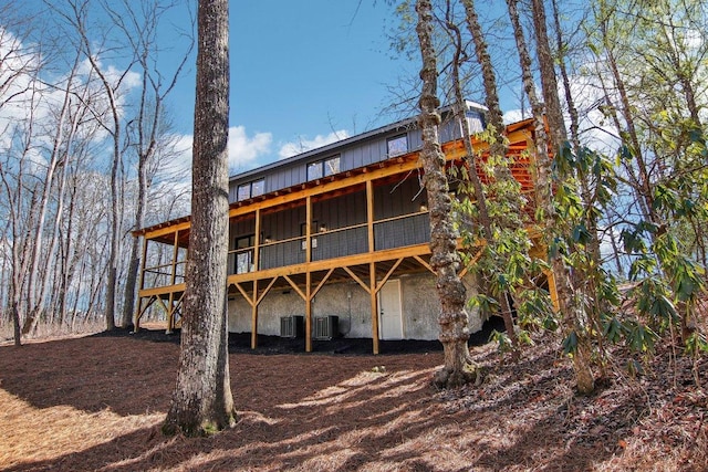 rear view of house featuring central AC unit and board and batten siding