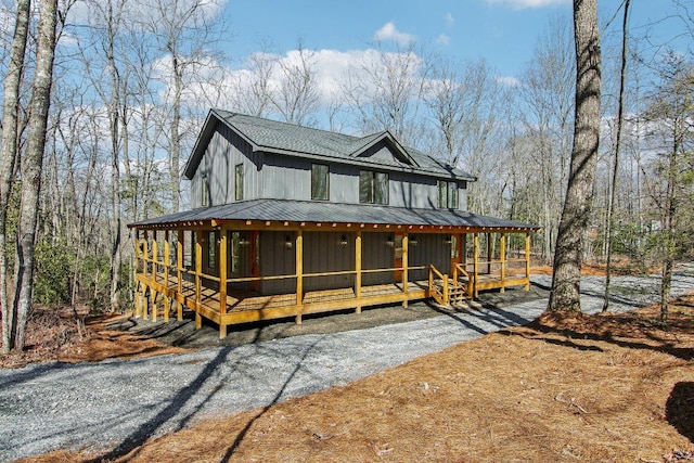 view of front of home with metal roof, a shingled roof, and a sunroom