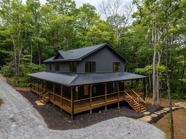 365 Cherokee Cir, Lake Toxaway, NC 28747 - view of front of property featuring covered porch, board and batten siding, a metal roof, roof with shingles, and a forest view